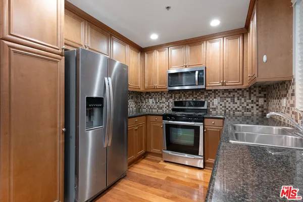 a kitchen with granite countertop a refrigerator and a sink