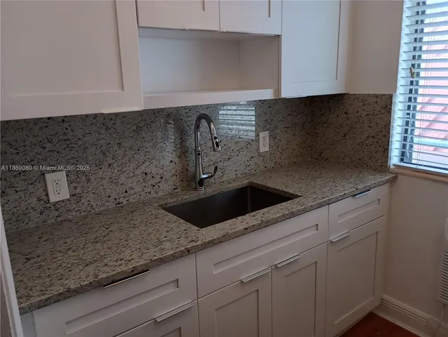 a kitchen with granite countertop a sink and cabinets