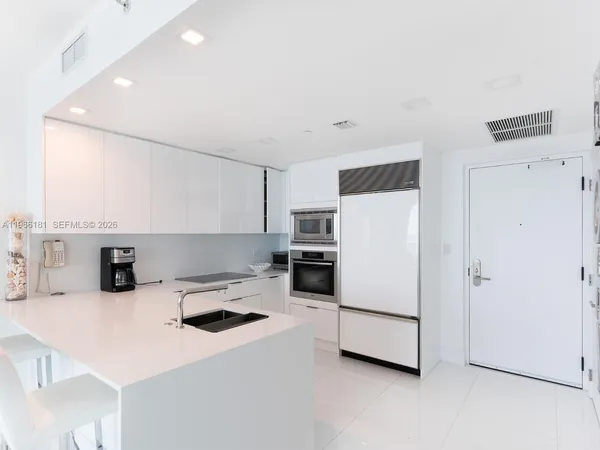 a kitchen with a refrigerator a stove and white cabinets