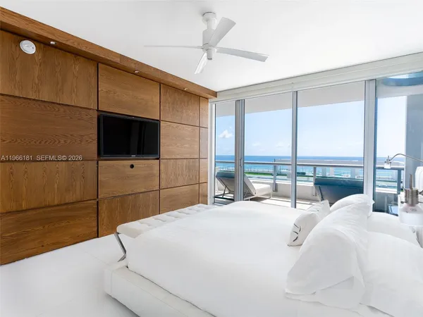 a large white bed sitting in a bedroom next to a window