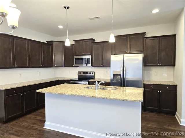 a kitchen with kitchen island granite countertop a sink a center island stainless steel appliances and cabinets