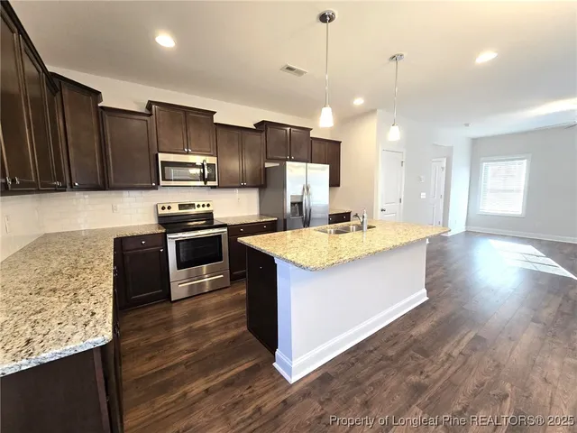 a kitchen with kitchen island wooden floors wooden cabinets counter space and appliances