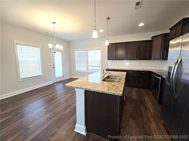 a kitchen with stainless steel appliances granite countertop wooden floors a stove a sink and a refrigerator