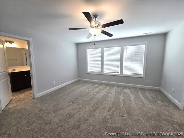 an empty room with chandelier fan and windows