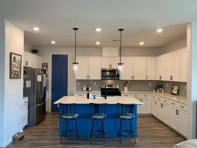 a kitchen with stainless steel appliances kitchen island granite countertop a refrigerator a stove a sink a dining table and chairs