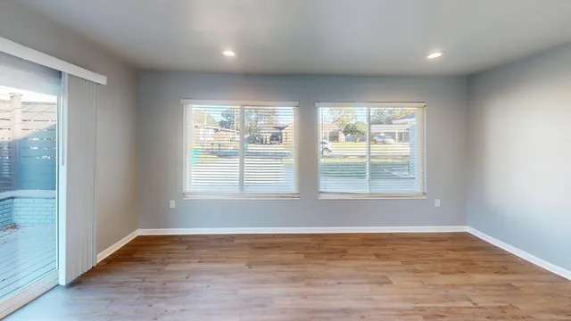 an empty room with wooden floor and windows
