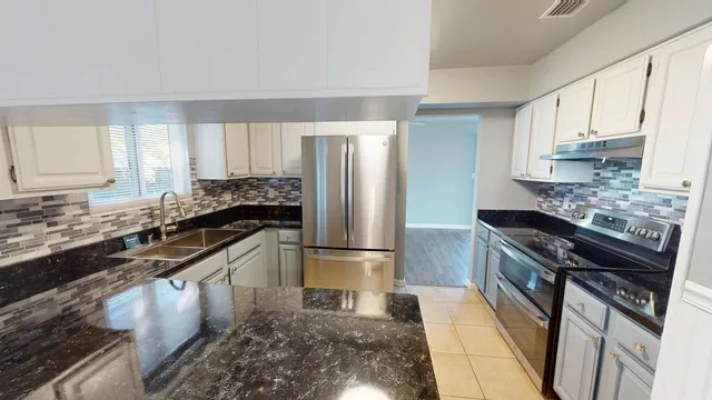 a kitchen with stainless steel appliances granite countertop a stove a sink and a refrigerator