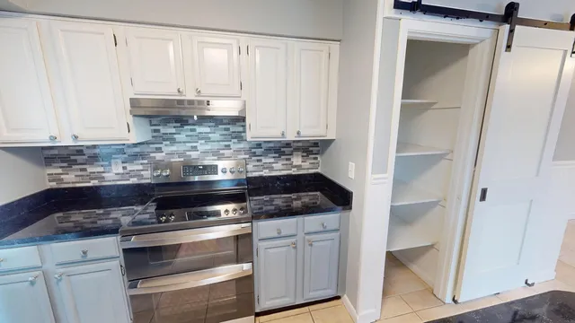 a kitchen with granite countertop white cabinets and stainless steel appliances