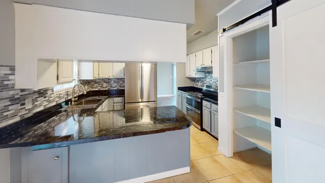 a kitchen with stainless steel appliances granite countertop a sink and a refrigerator