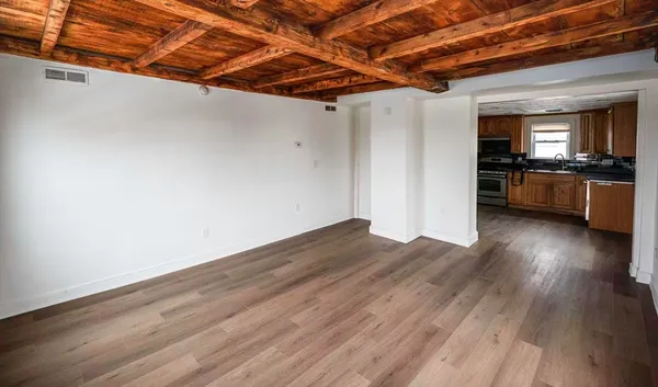 a view of a room with wooden floor and a kitchen