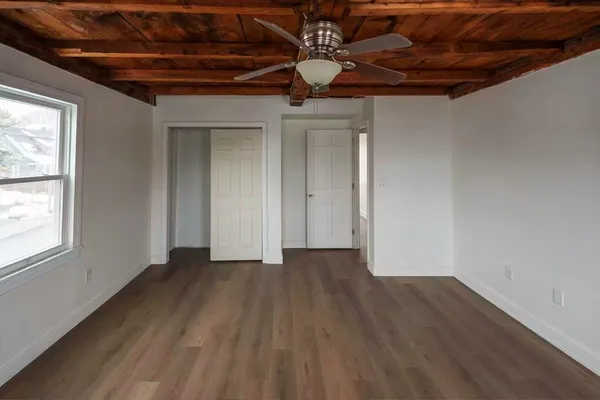 a view of an empty room with wooden floor and a window
