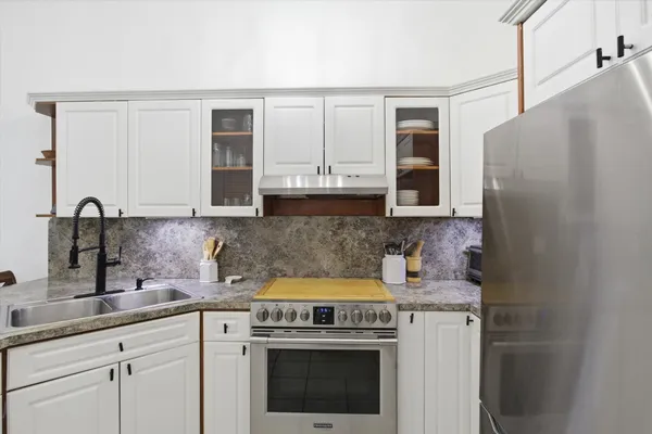 a kitchen with stainless steel appliances granite countertop a stove a sink and a refrigerator