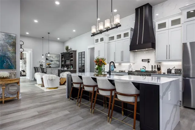 a kitchen with stainless steel appliances kitchen island granite countertop a dining table chairs and white cabinets
