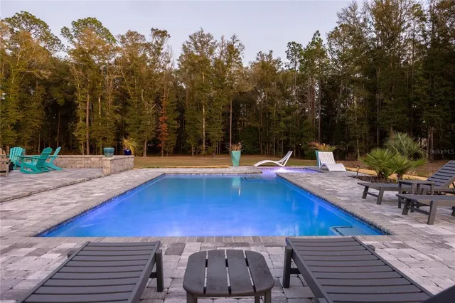 a view of a swimming pool with a bench and trees