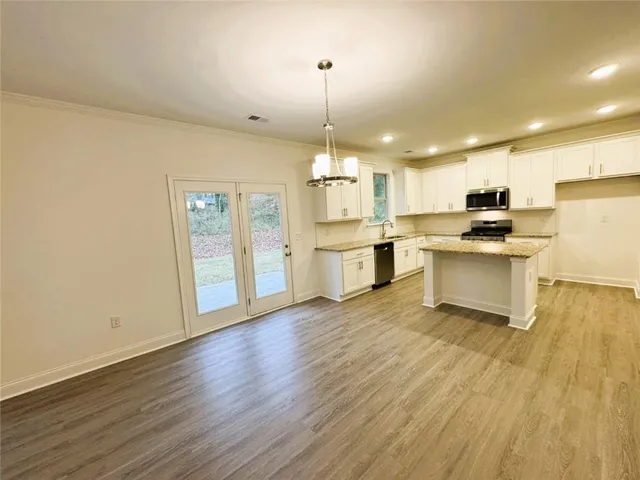 a kitchen with stainless steel appliances granite countertop a sink a stove a refrigerator and island with wooden floor