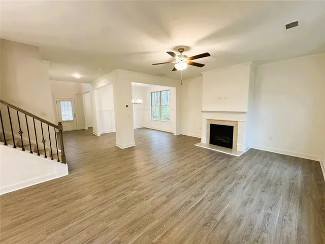 a view of an empty room with wooden floor and a fireplace