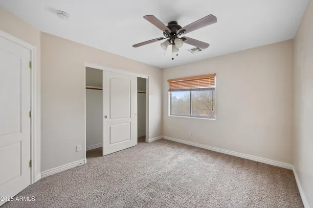 an empty room with windows and ceiling fan