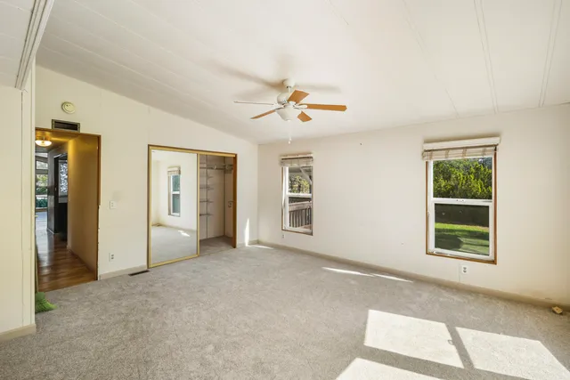 an empty room with windows and ceiling fan