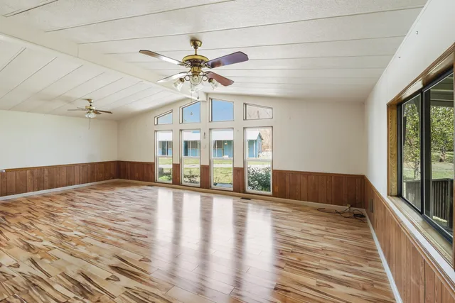 a view of an empty room with a window and wooden floor