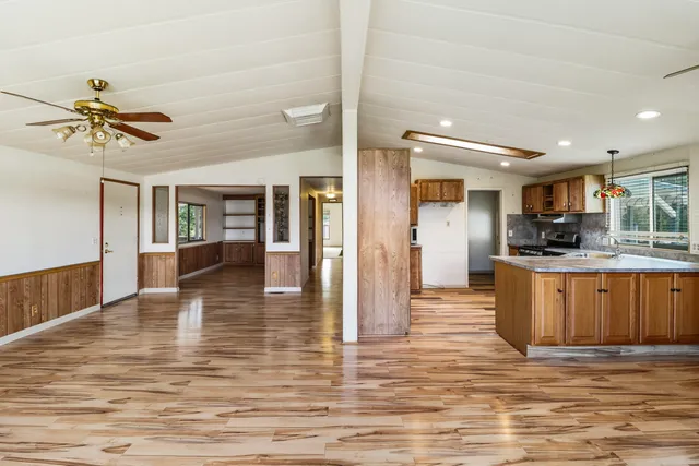 a view of a kitchen with kitchen island granite countertop a stove cabinets and wooden floor