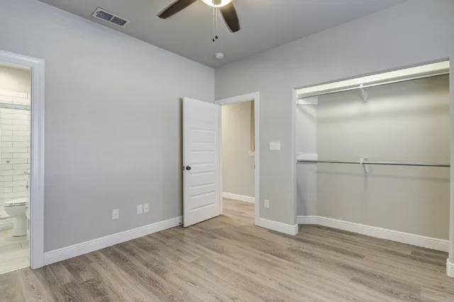 an empty room with wooden floor cabinet and windows