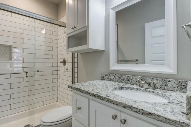 a bathroom with a granite countertop sink toilet and shower