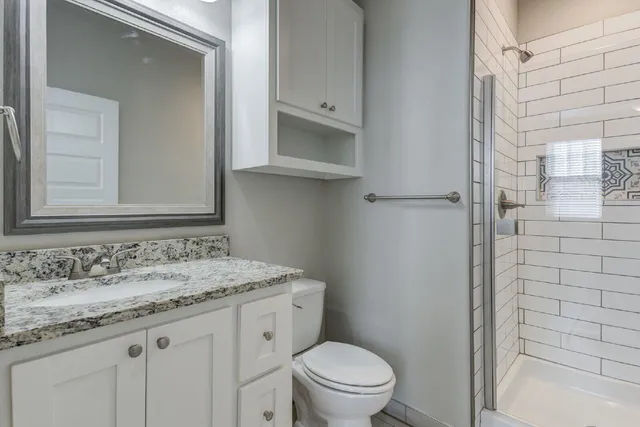 a bathroom with a granite countertop toilet sink and mirror