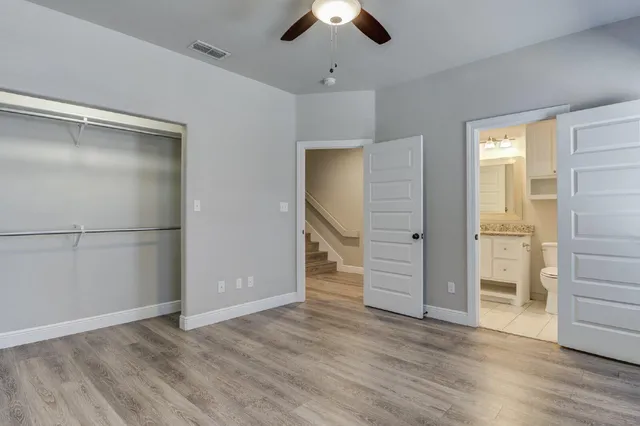 an empty room with wooden floor closet and windows