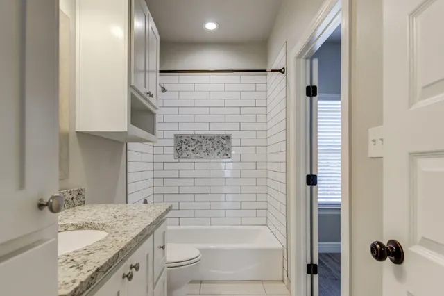 a bathroom with a granite countertop sink a toilet and shower