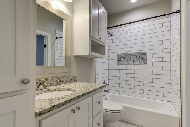 a bathroom with a granite countertop sink toilet and shower