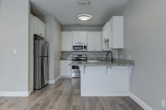 a kitchen with stainless steel appliances granite countertop a refrigerator stove and white cabinets