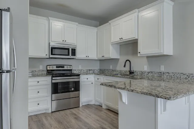a kitchen with granite countertop white cabinets and stainless steel appliances