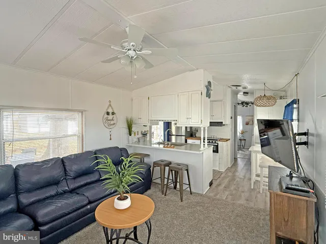 a living room with furniture kitchen view and a chandelier