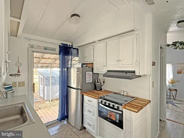 a kitchen with stainless steel appliances granite countertop a refrigerator a sink and white cabinets