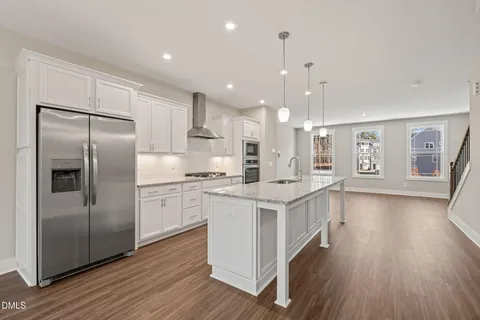 a kitchen with stainless steel appliances granite countertop a refrigerator a sink dishwasher a stove and white countertops with wooden floor