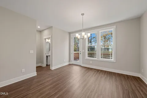 a view of an empty room with wooden floor fridge and a window