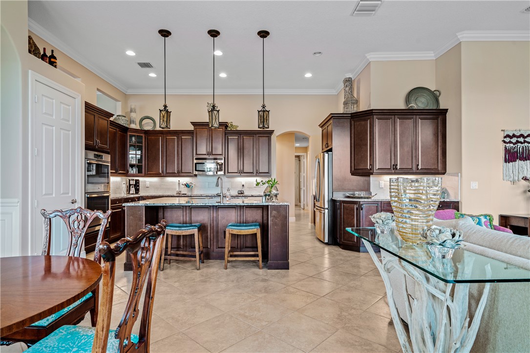 8250 Halbert Lane Vero Beach, FL 32968 - Photo 12 of 36 a kitchen with stainless steel appliances kitchen island granite countertop a table chairs and a refrigerator
