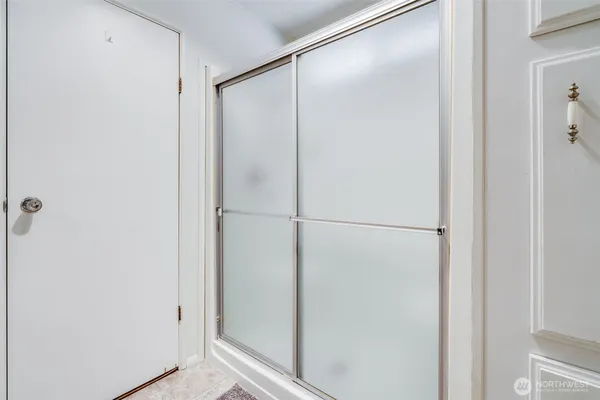 a view of a hallway with wooden floor and a bathroom