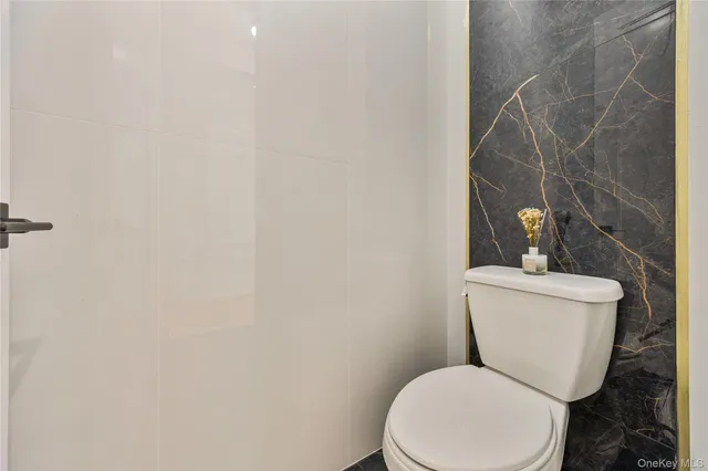 a white toilet sitting next to a white wall