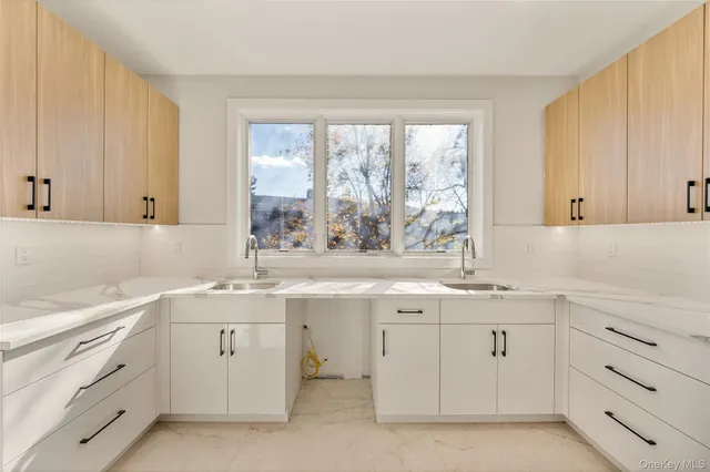 a kitchen with white cabinets window and sink