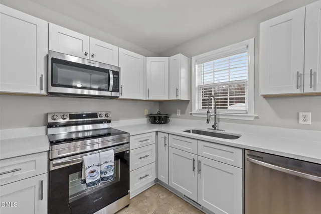 a kitchen with cabinets appliances a sink and a window