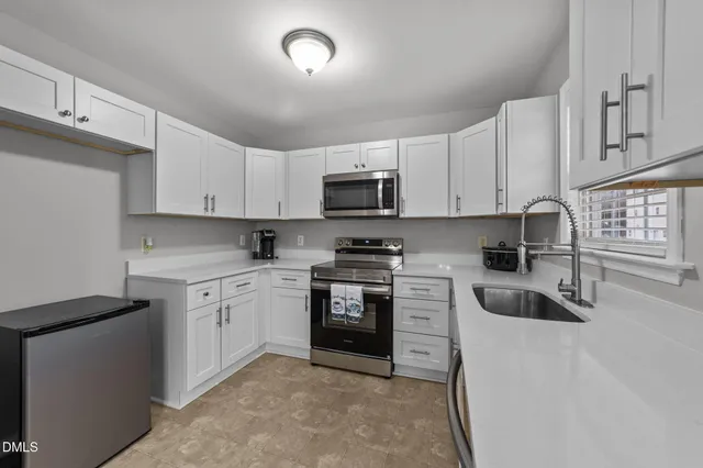 a kitchen with cabinets stainless steel appliances a sink and a window