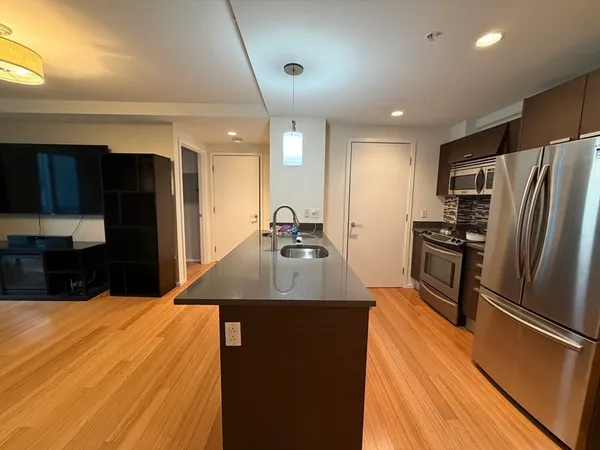 a kitchen with stainless steel appliances kitchen island granite countertop a refrigerator a sink dishwasher a stove with wooden cabinets