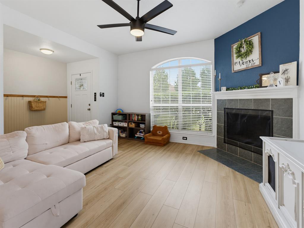 600 Stirling Road Rhome, TX 76078 - Photo 4 of 38 Living area featuring wood-finish flooring, a contemporary fireplace with a tiled surround and hearth, and a large arched window with horizontal blinds