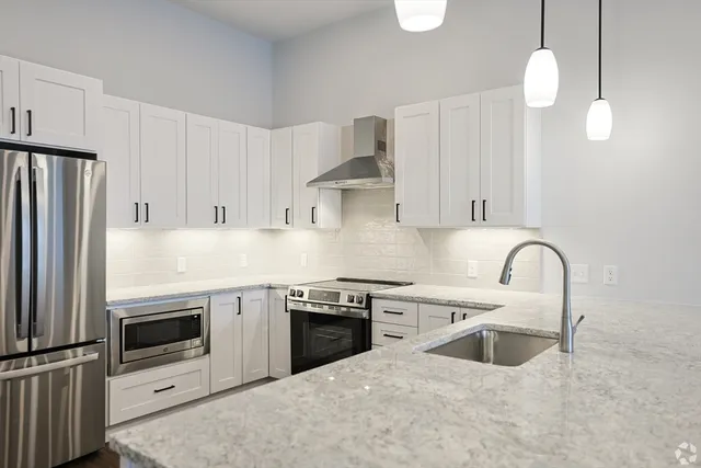 a kitchen with stainless steel appliances granite countertop a sink a stove and refrigerator