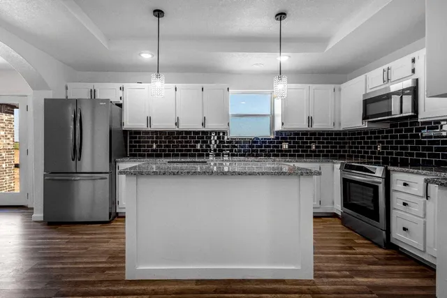 a kitchen with stainless steel appliances a refrigerator a sink dishwasher a stove and white countertops with wooden floor