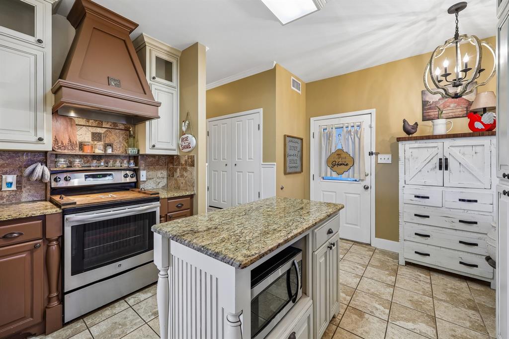 331 Radecke Road Krum, TX 76249 - Photo 21 of 40 Kitchen featuring a central island with granite countertop, built-in microwave, and beadboard paneling