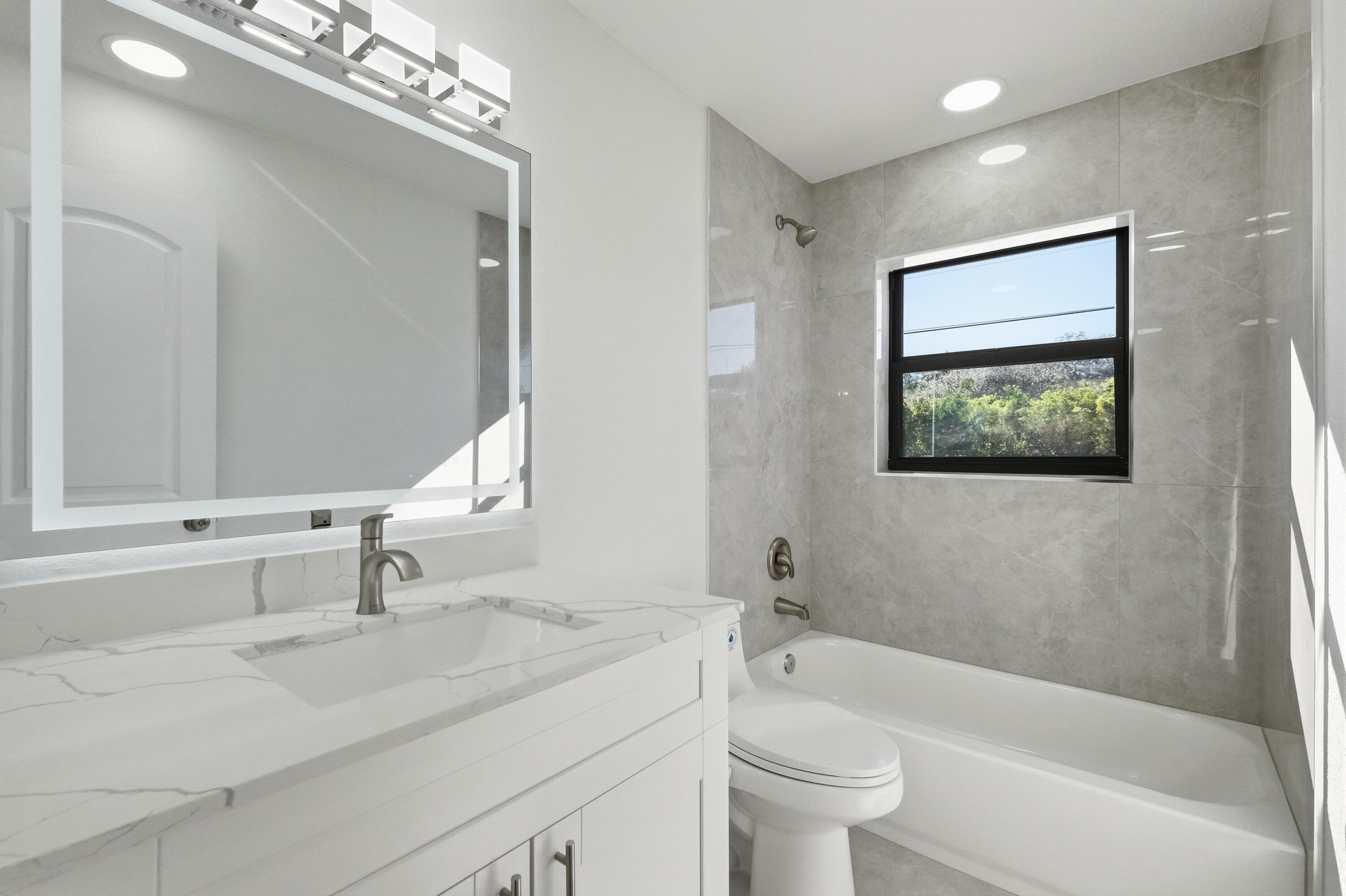 22390 Southwest 66th Avenue Boca Raton, FL 33428 - Photo 29 of 58 a bathroom with a sink a toilet a mirror a vanity a bathtub and shower