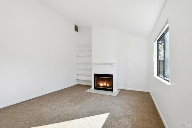 a view of an empty room with a fireplace and a window