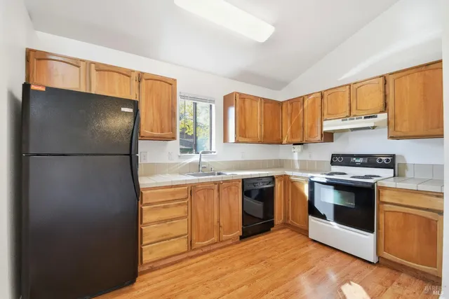 a kitchen with stainless steel appliances granite countertop a refrigerator a sink dishwasher a stove with wooden cabinets